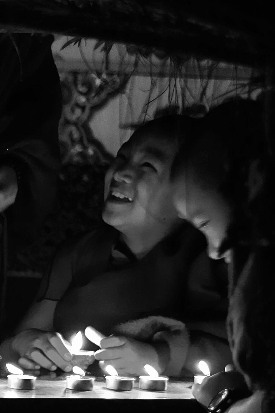 Dos jóvenes monjes ríen a la luz de las velas en el monasterio de Kopan